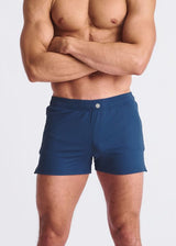 Man wearing blue swim shorts against a plain background