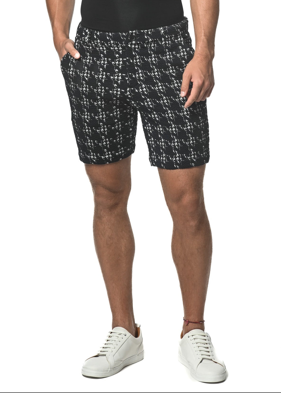 A man wearing a black V-neck t-shirt and navy houndstooth patterned shorts with a slim fit and 8-inch inseam, standing against a white background.