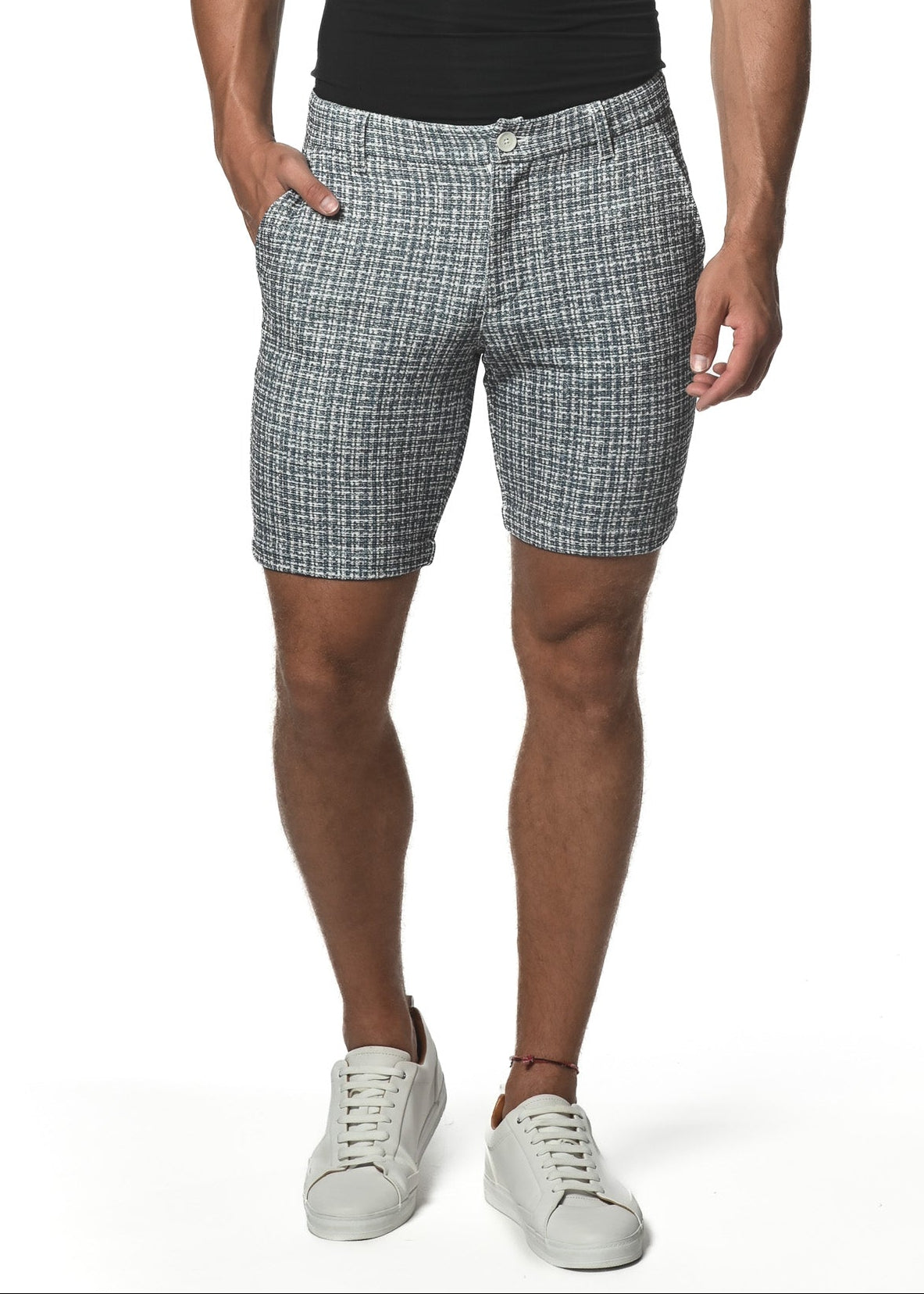A man wearing a black V-neck t-shirt and grey micro check pattern shorts with a 8-inch inseam, standing against a white background.