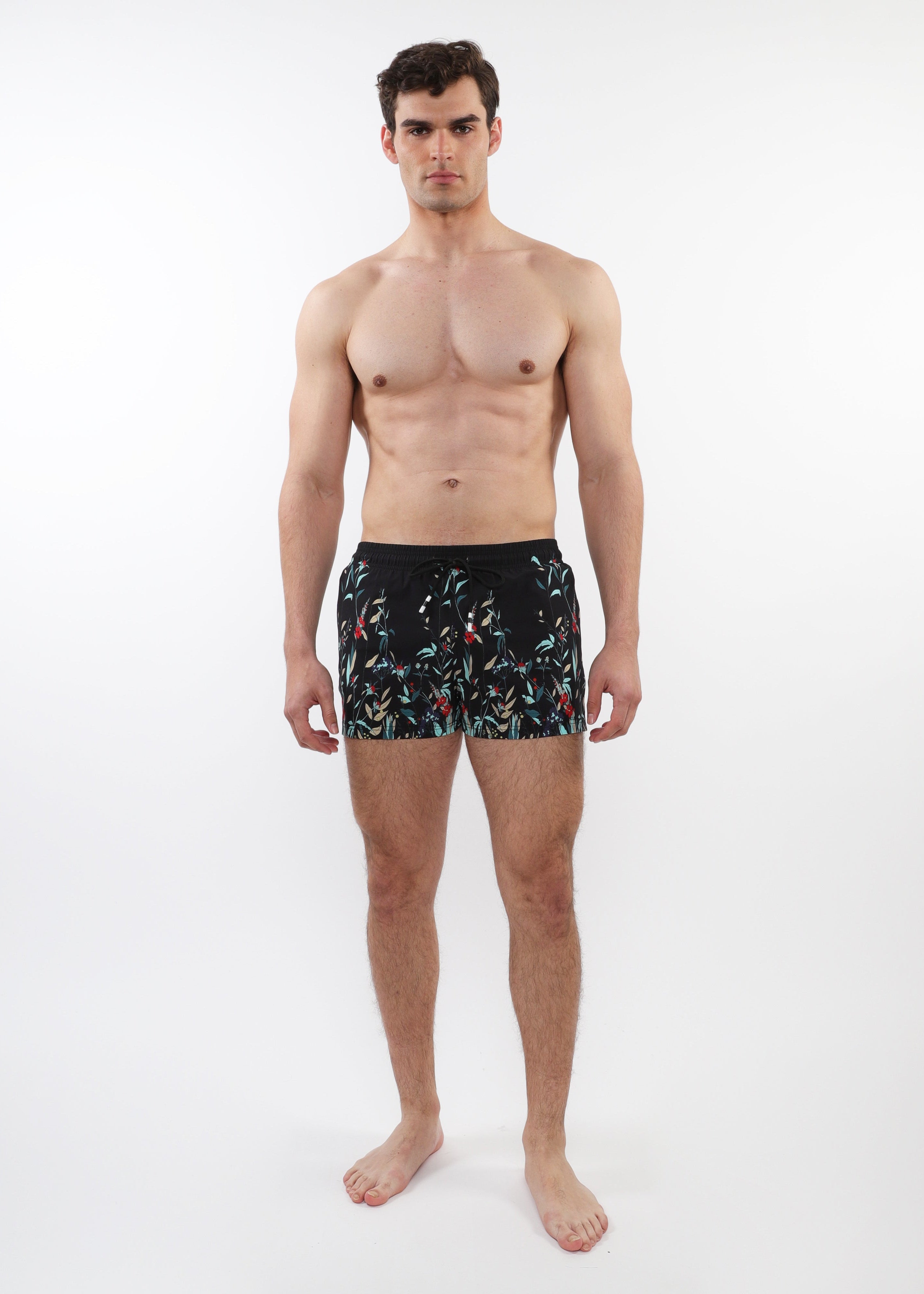 Man wearing black swim shorts with a colorful pattern on a white background