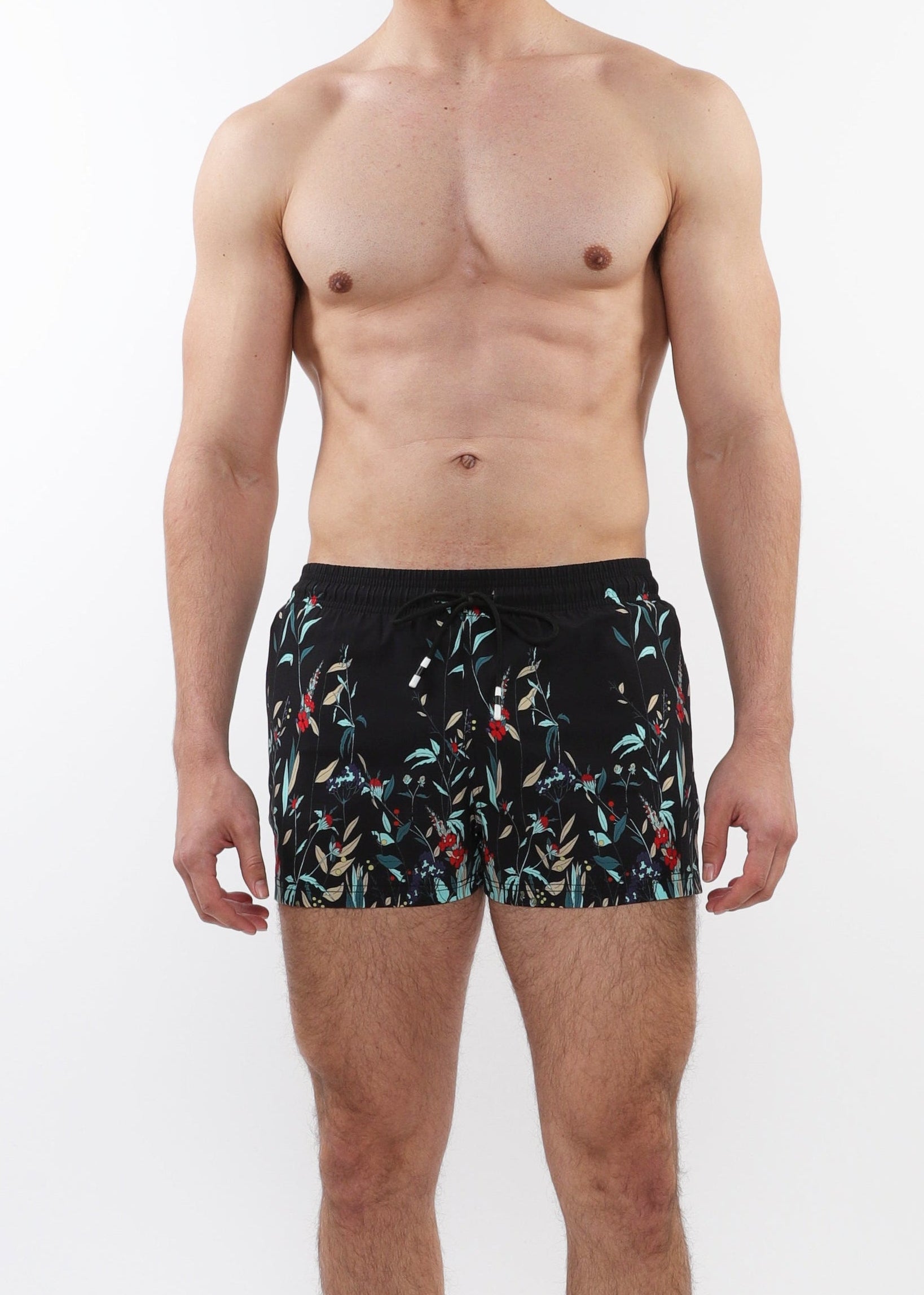 Man wearing black swim shorts with a colorful pattern on a white background