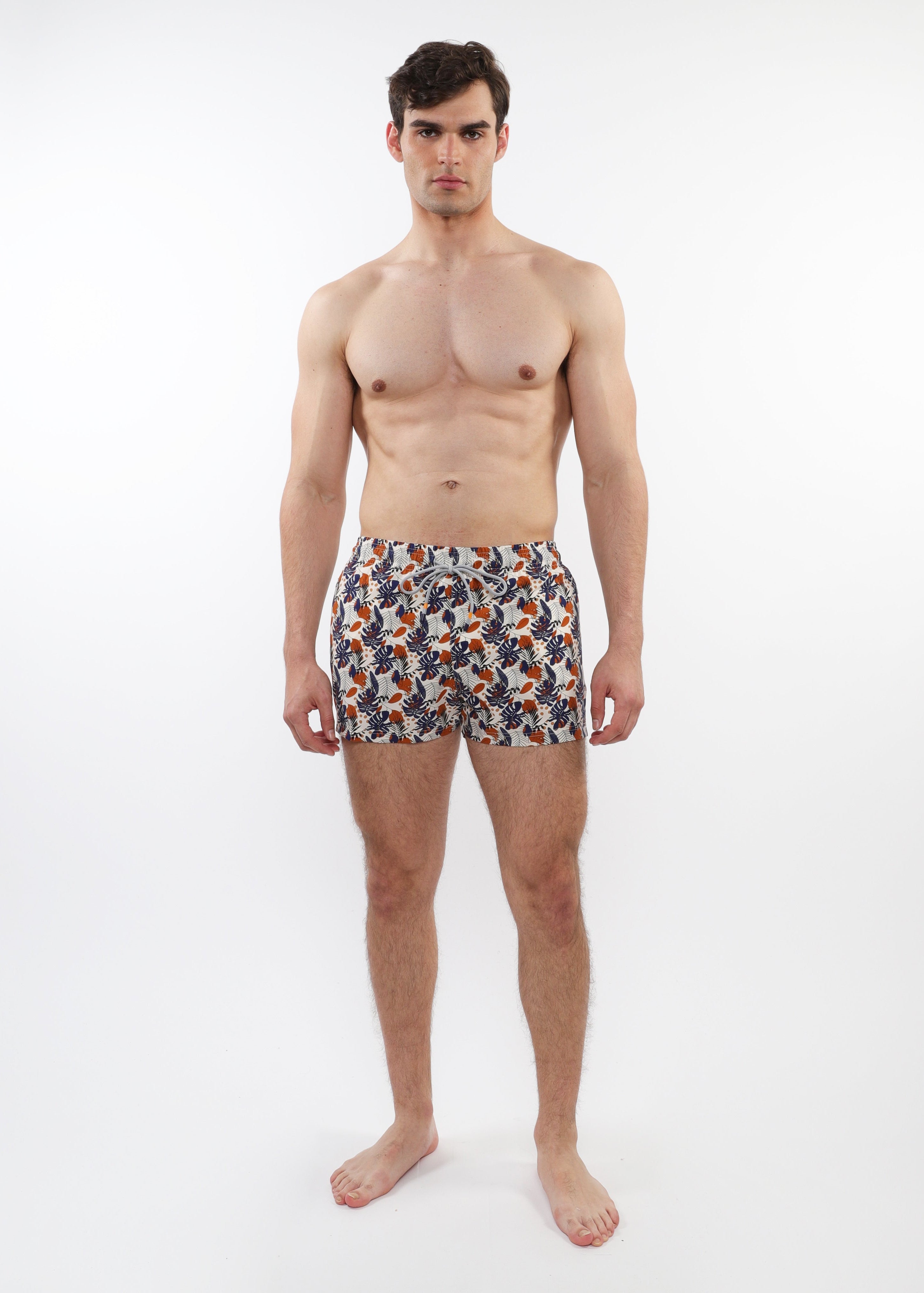 Man wearing patterned swim shorts on a white background