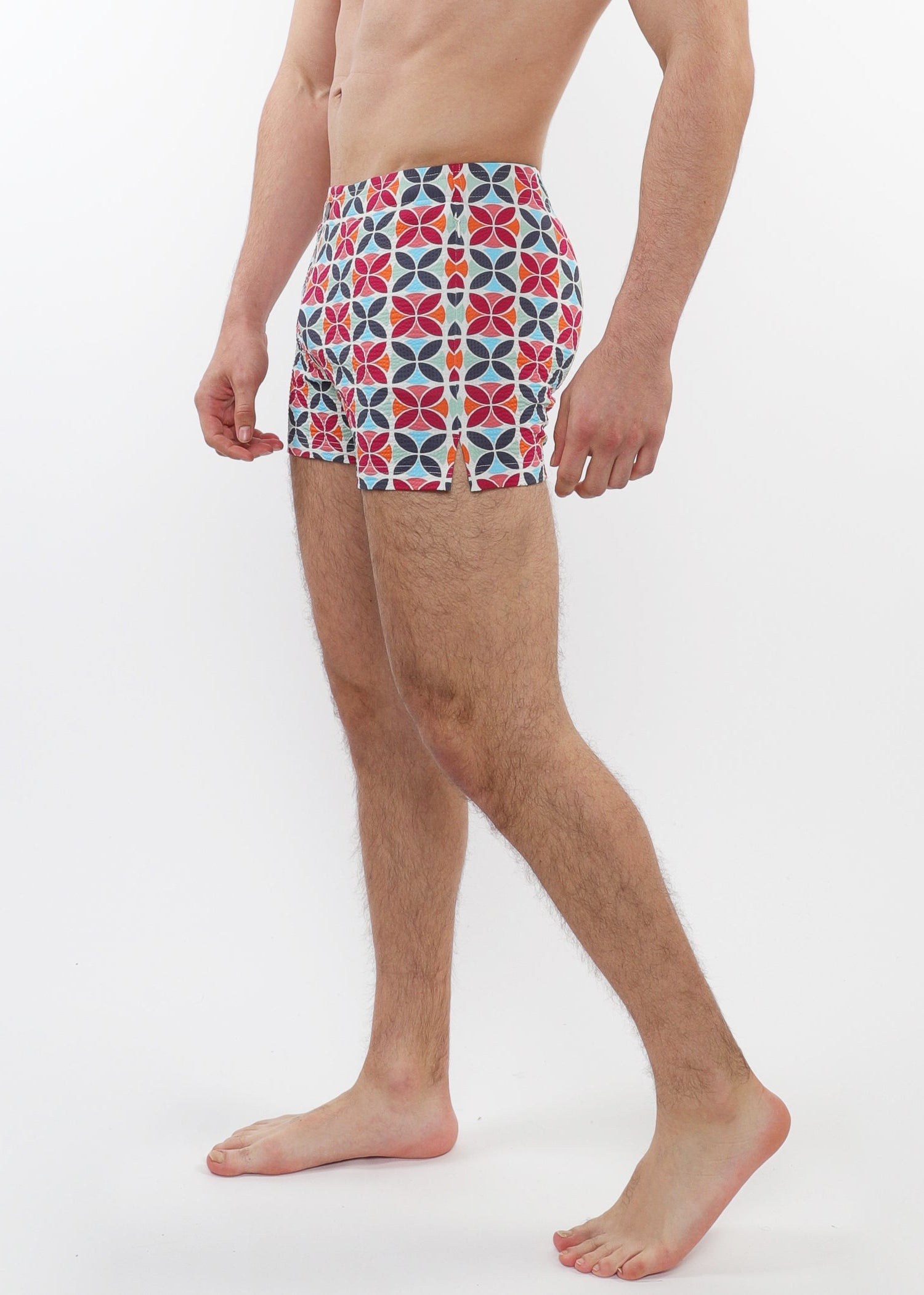 Person wearing colorful patterned swim shorts on a white background