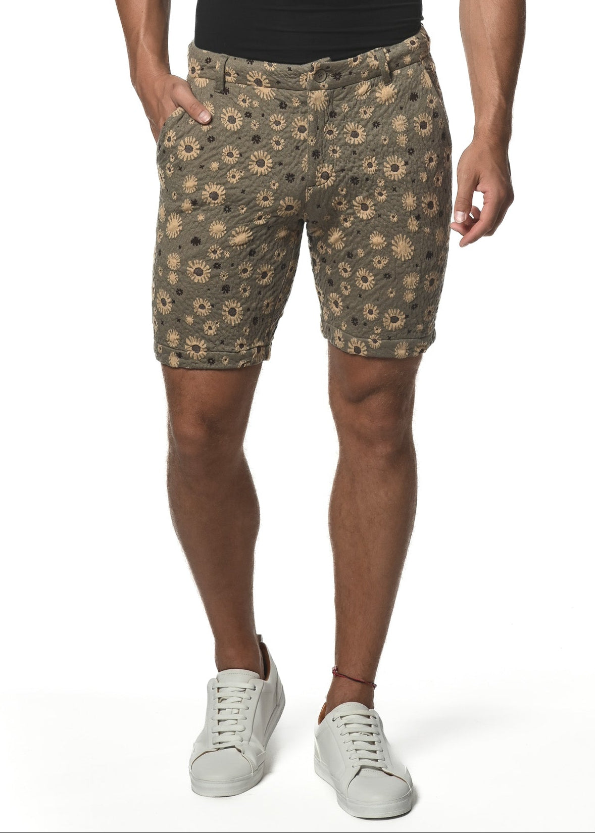 A man wearing a black V-neck t-shirt and beige/khaki floral print knit shorts with a stretch waistband, belt loops, side pockets, and button-through welt pockets.