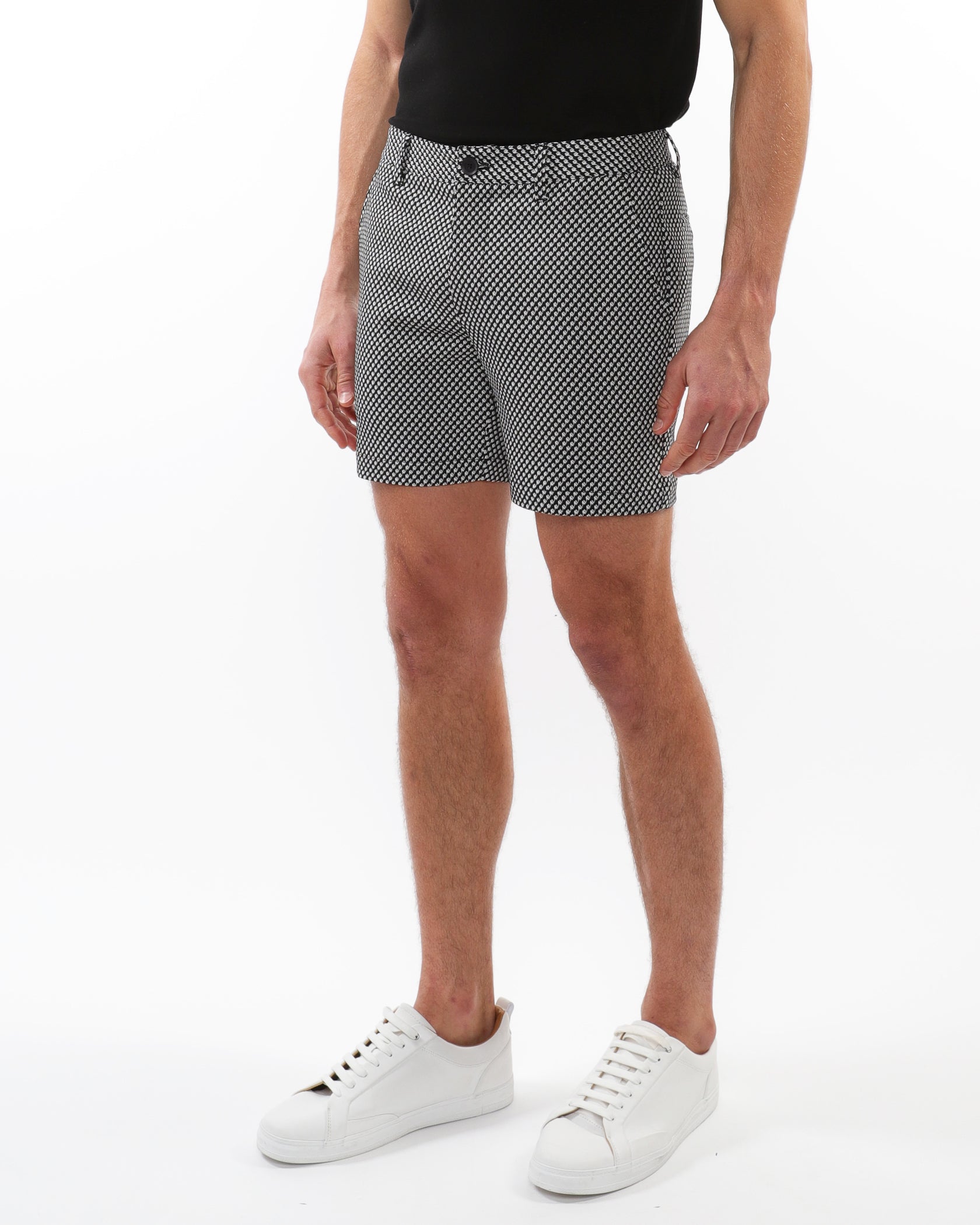 Person wearing patterned shorts and white sneakers on a white background