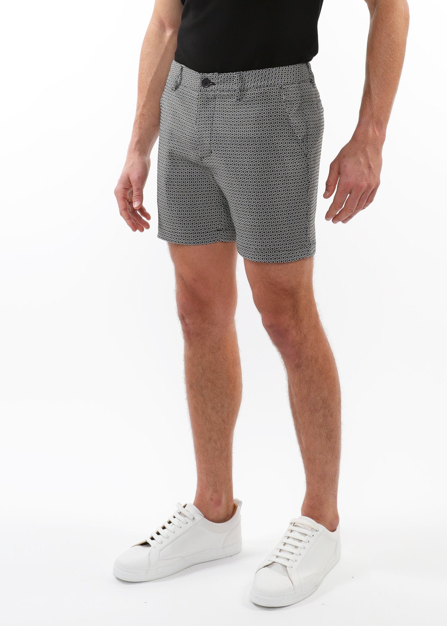 Person wearing gray patterned shorts and white sneakers on a white background