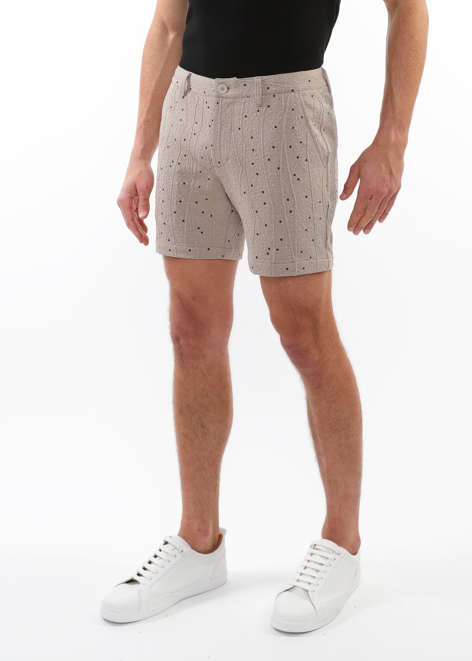 Person wearing beige patterned shorts on a white background