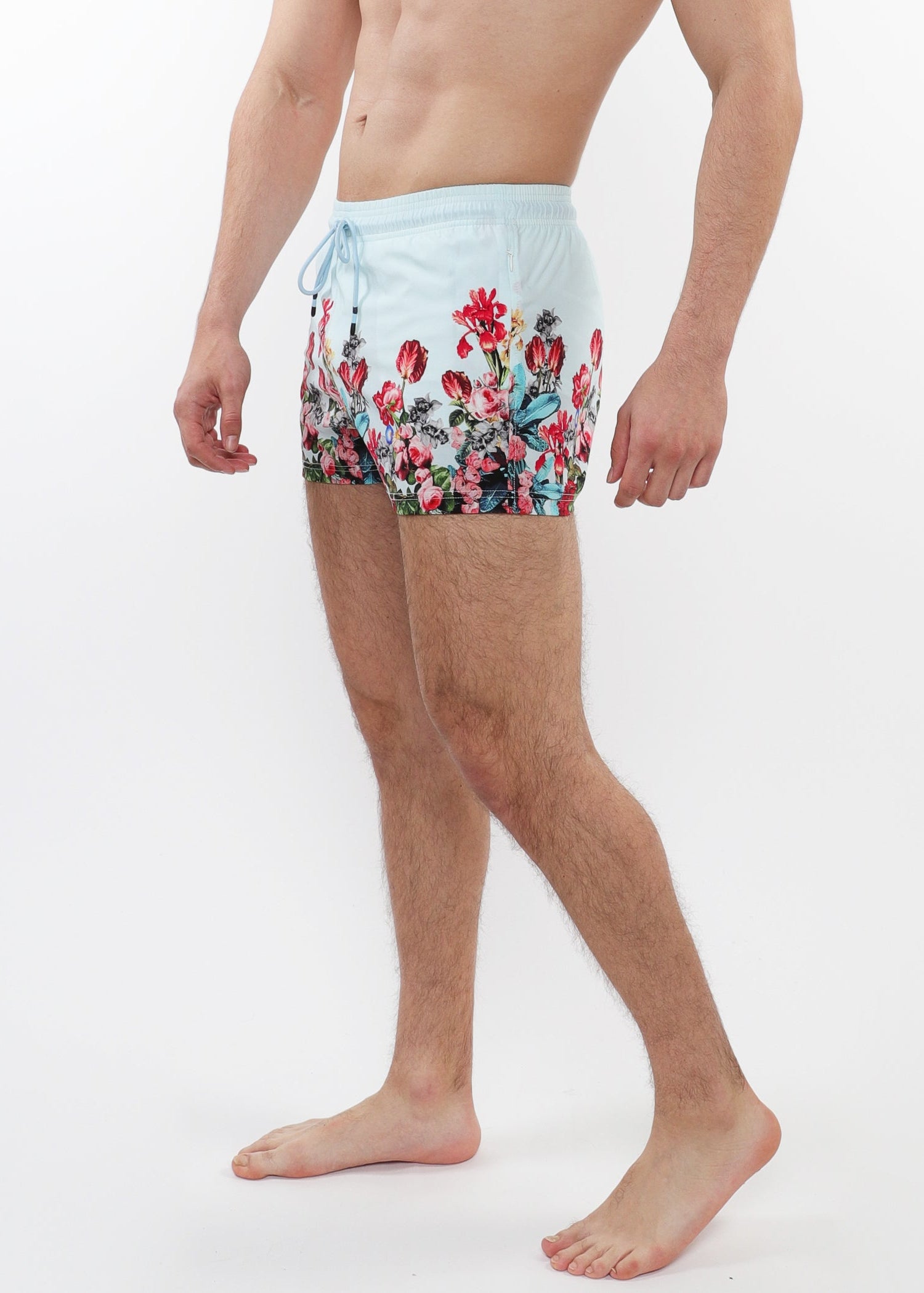 Person wearing floral swim shorts on a white background