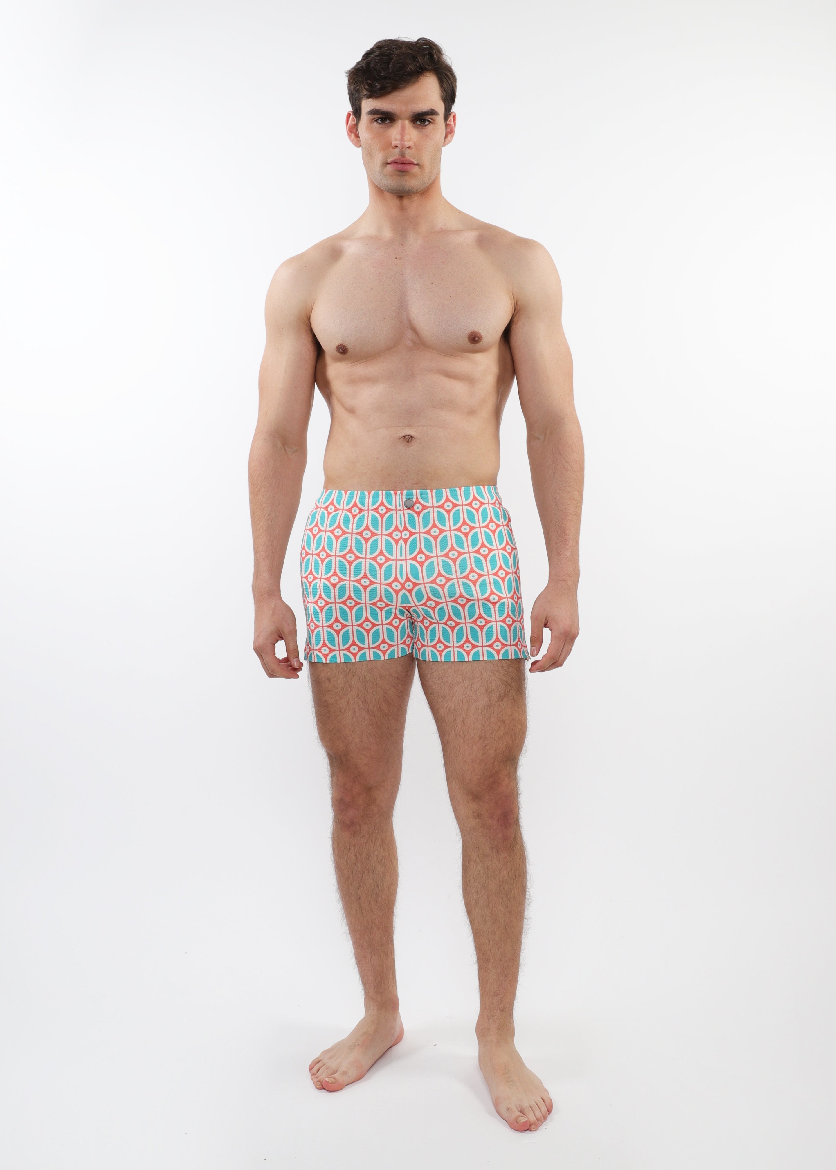 Man wearing patterned swim shorts on a white background