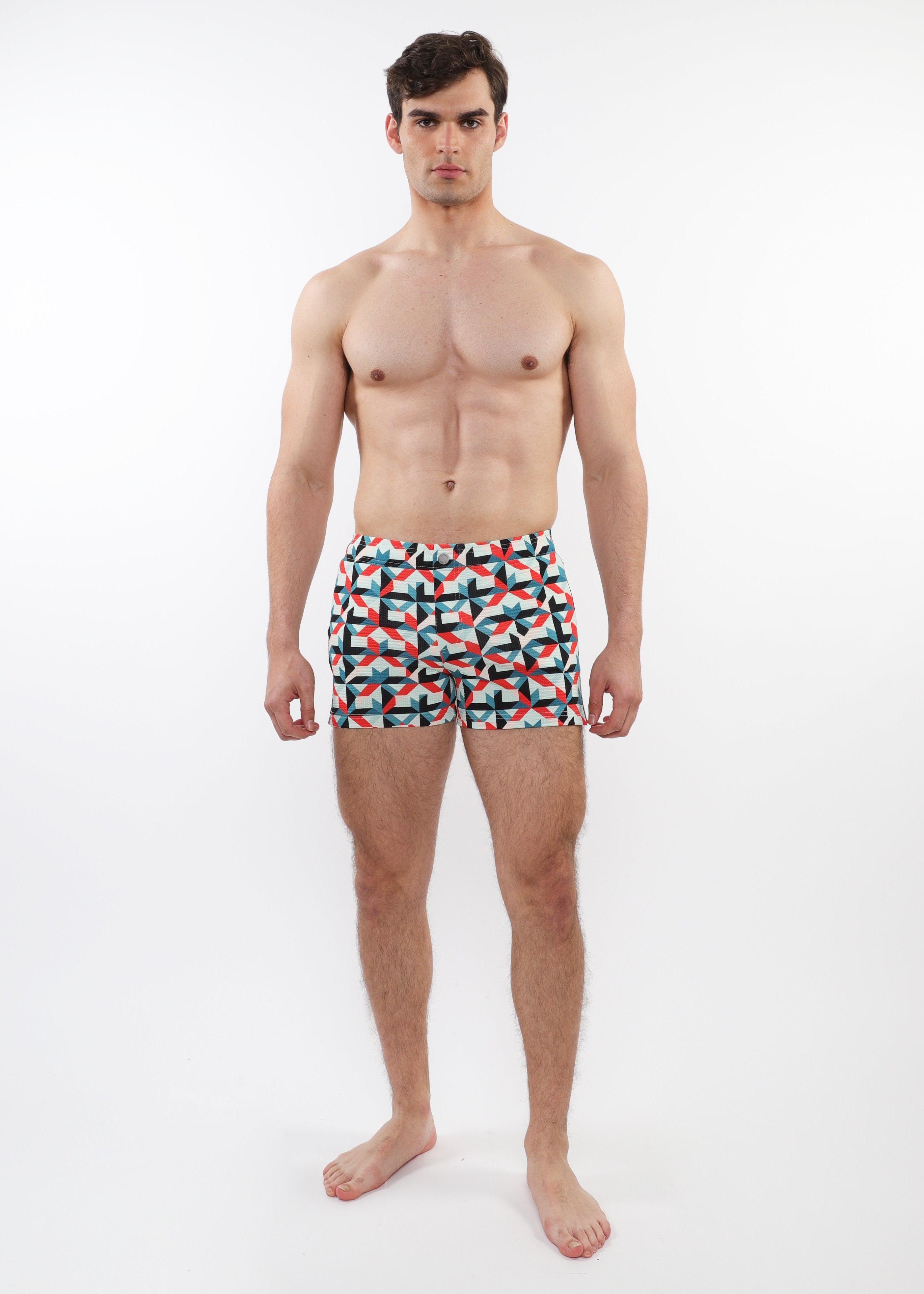 Man wearing colorful geometric patterned swim shorts on a white background