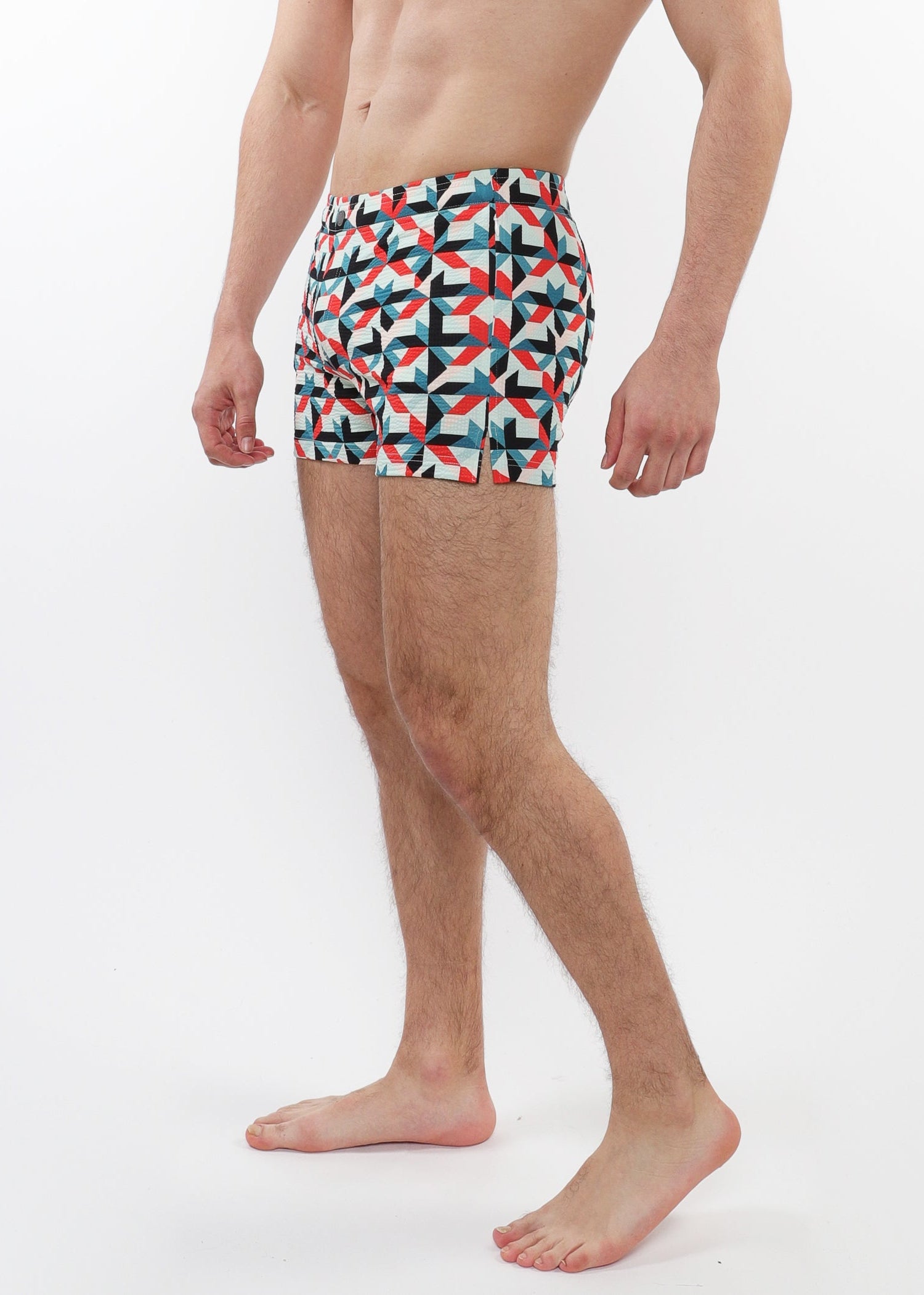 Person wearing colorful geometric-patterned swim shorts on a white background
