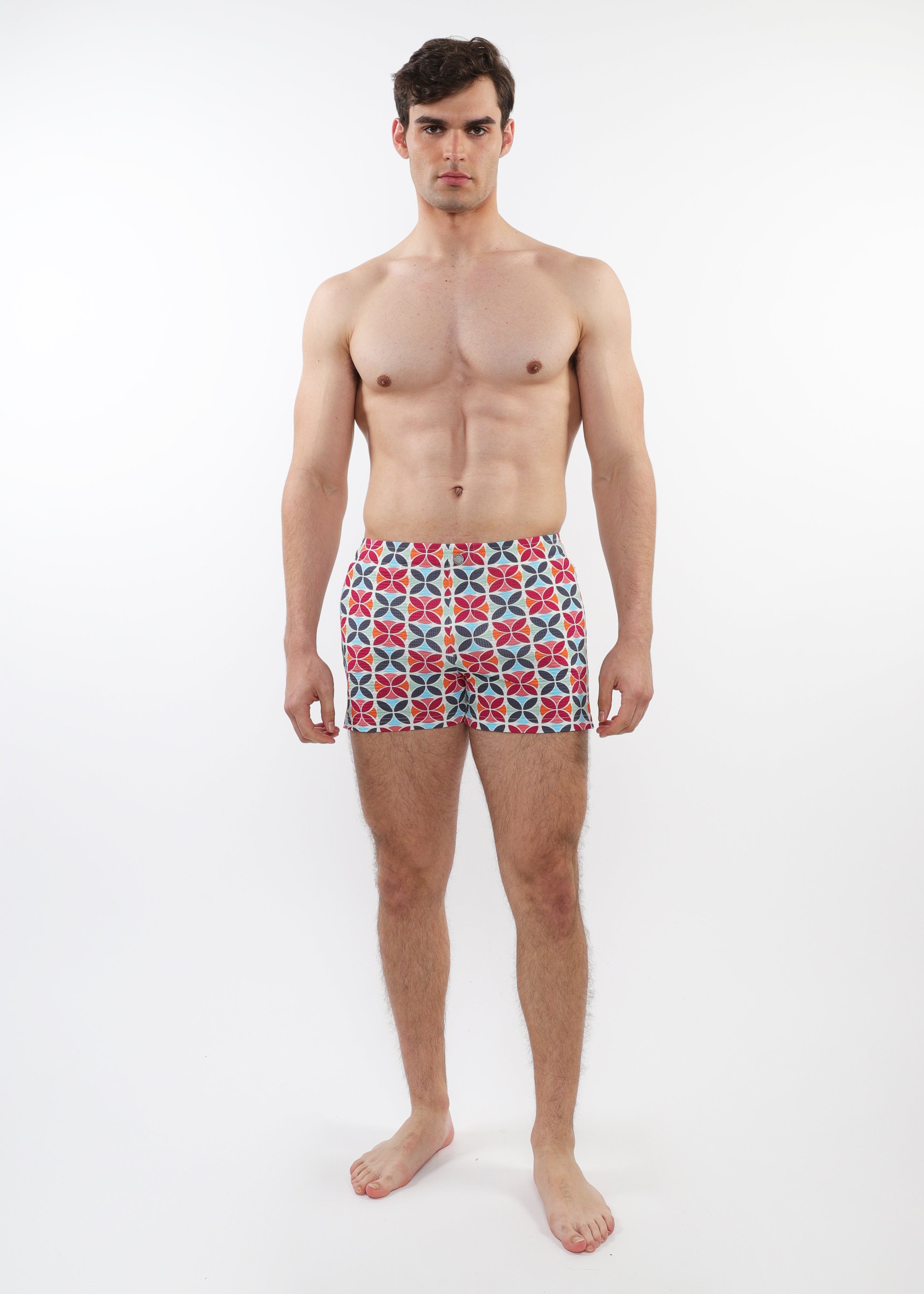 Man wearing patterned swim shorts on a white background