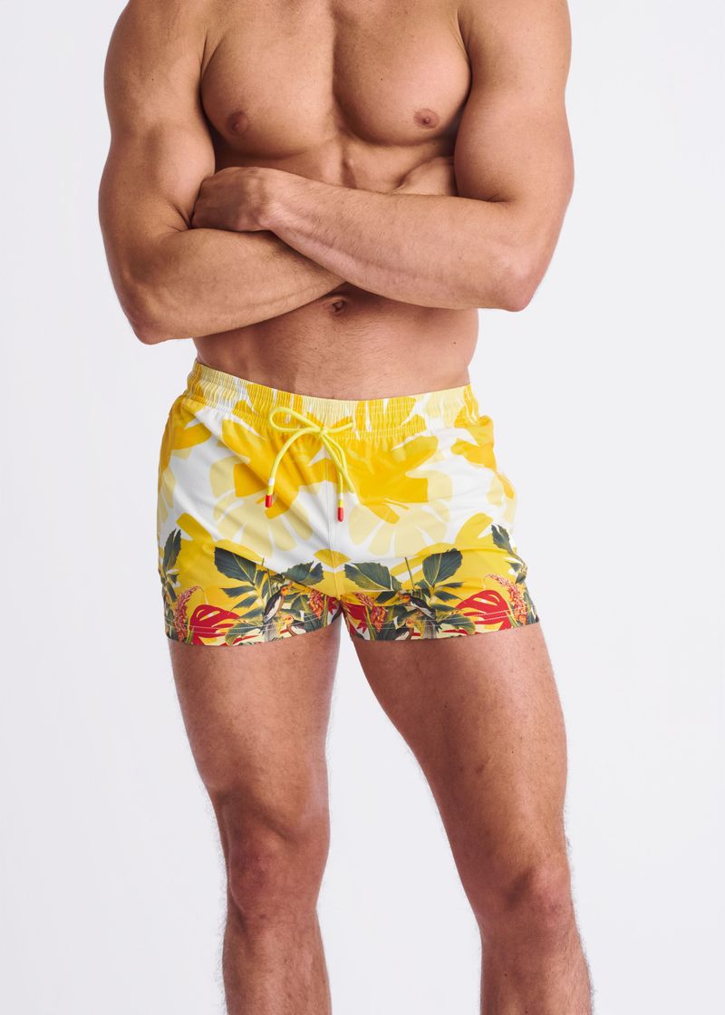 Man wearing a colorful floral swim shorts on a white background